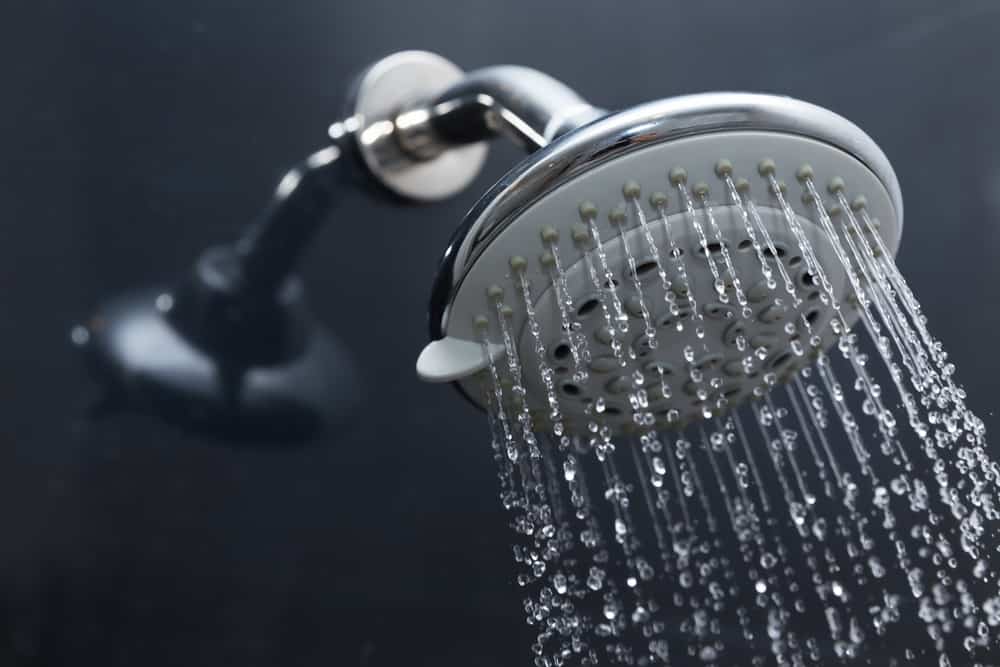 Shower head in bathroom with water drops flowing