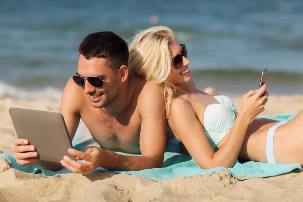 Happy couple with tablet pc sunbathing