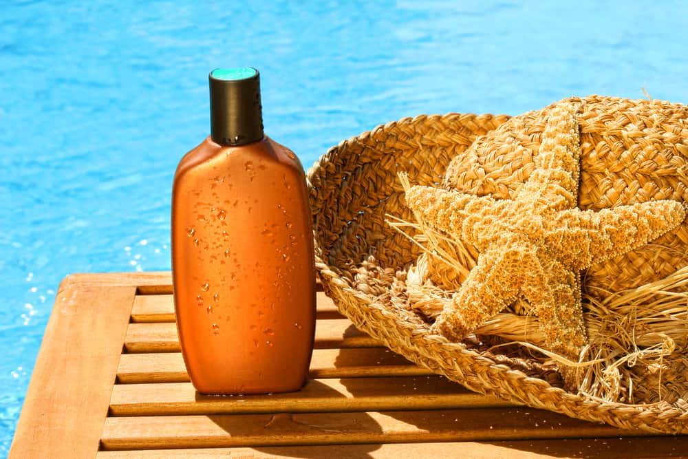 Tanning lotion with sun hat by the pool