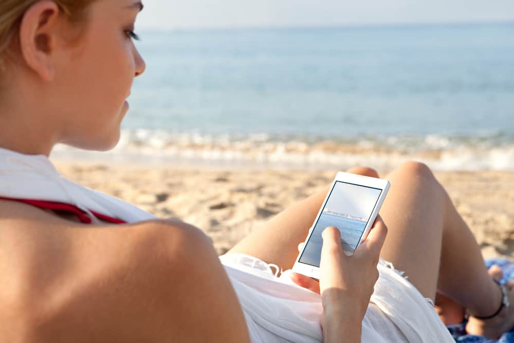 Woman on a beach by the sea using phone