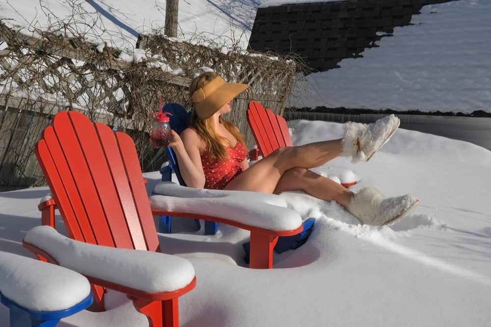 Young Woman in a Red Bathing Suit Sitting on Snow Covered Chairs in the Backyard