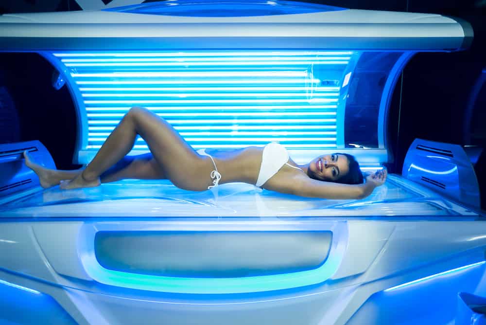 Young woman in modern tanning bed